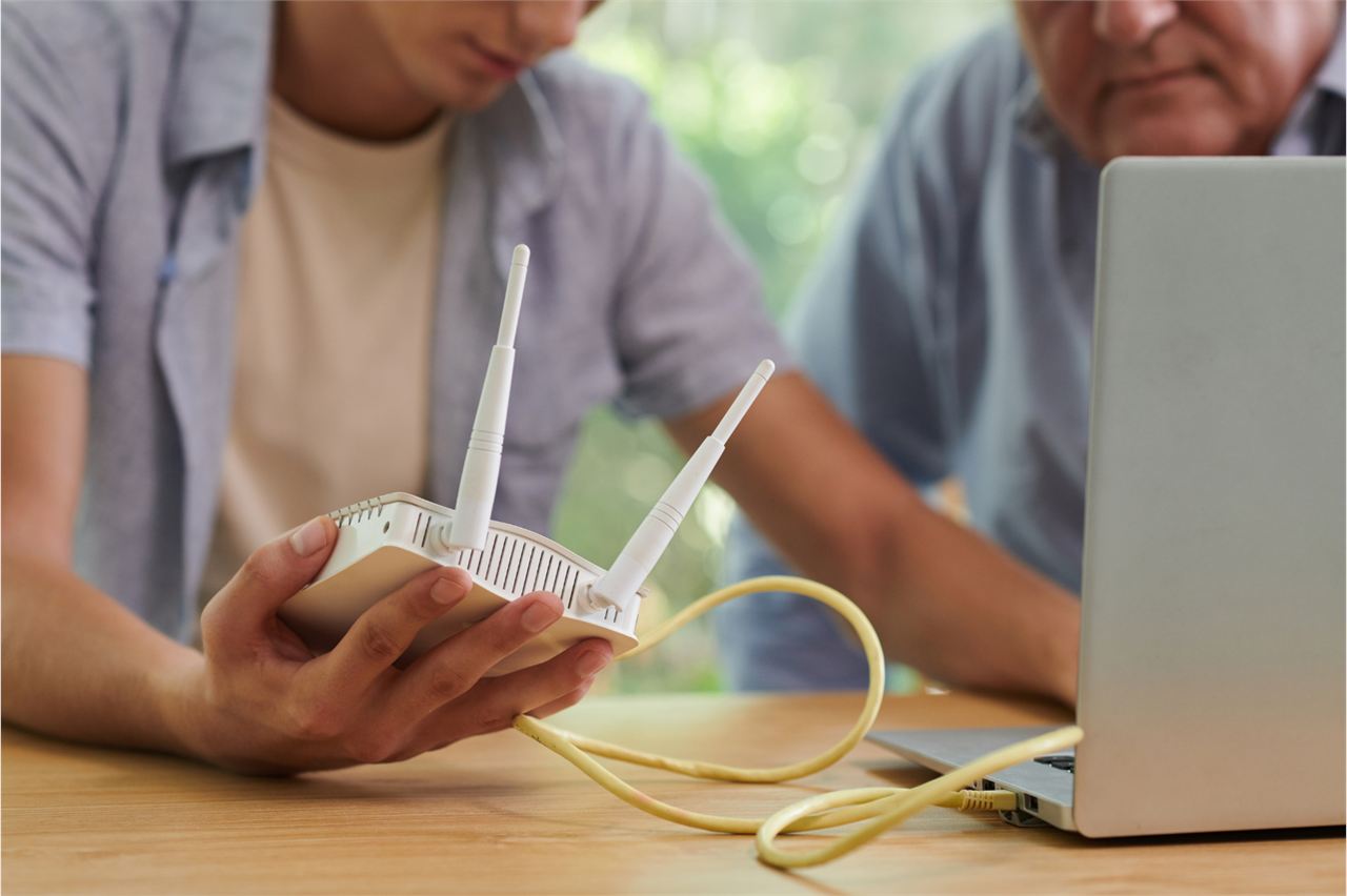 Techniker installiert einen WLAN-Router und verbindet ihn mit einem Laptop